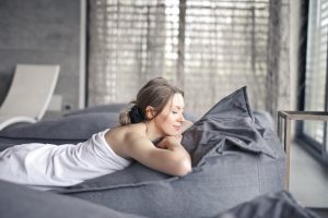 woman-in-white-tank-top-lying-on-gray-bed-3673941