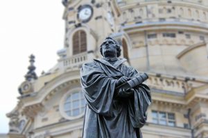 gray-concrete-statue-of-man-holding-book-beside-brown-34704