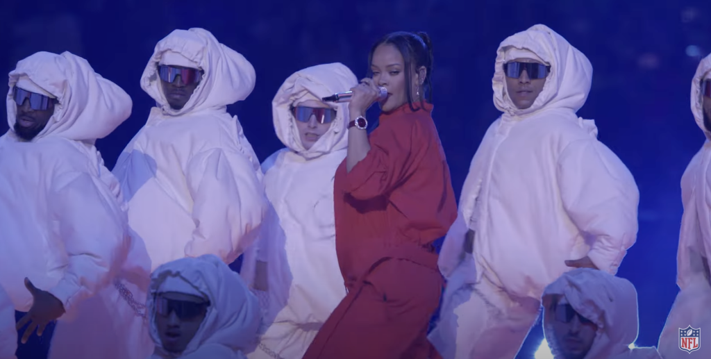 Ein Bild von Rihanna mit weiß-gekleideten Tänzern bei der Halbzeitshow der Superbowl.