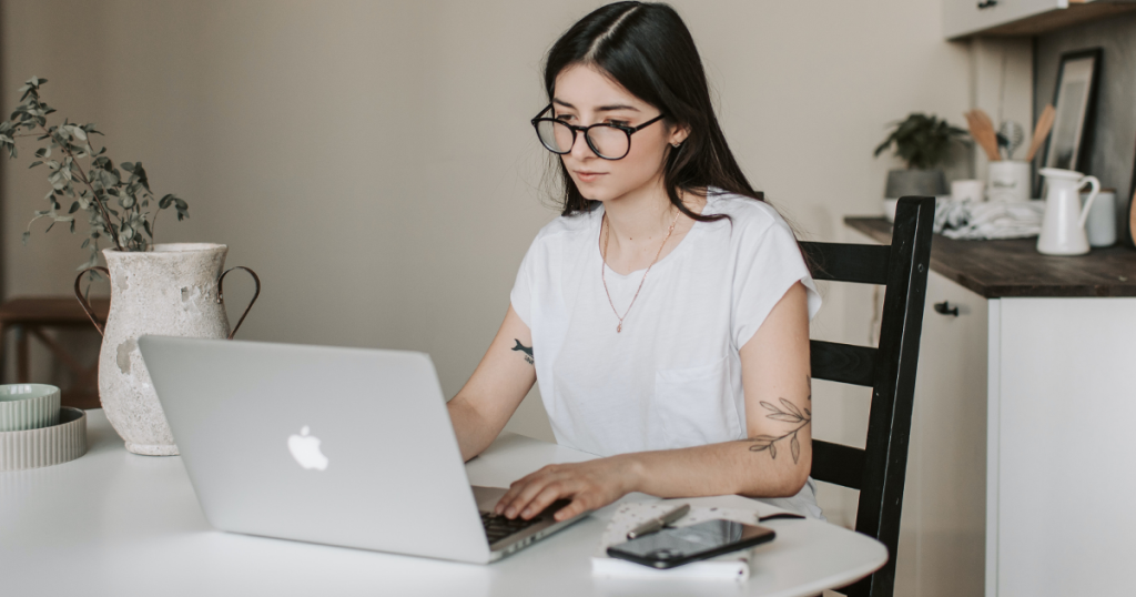 Eine junge Frau sitzt an einem Tisch hinter einem Laptop. Gehört zu einem Blog über Praktikanten.