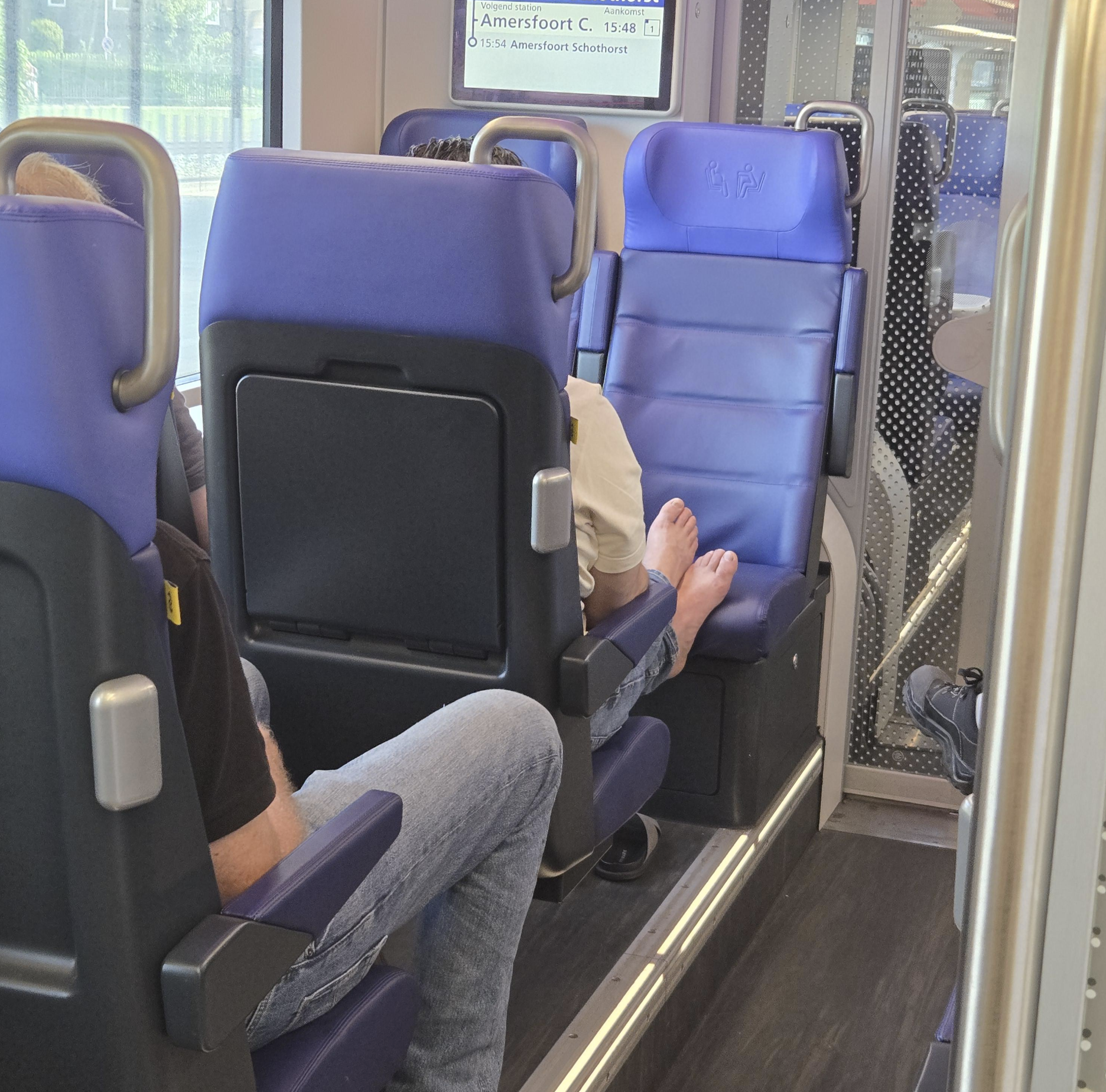 man met voeten op stoel van de trein